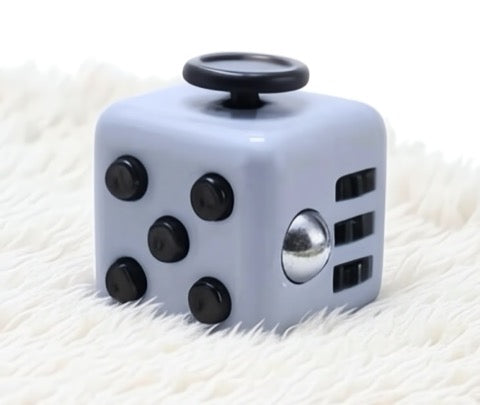 Fidget cube with black buttons on a white textured surface