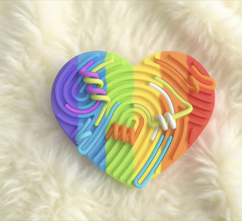 Heart-shaped rainbow-colored silicone straw holder on a soft white background