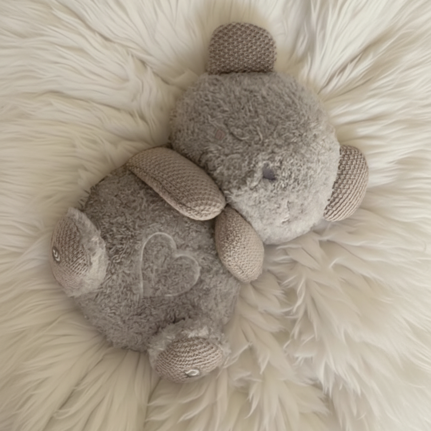 Two gray stuffed animals on a fluffy white surface