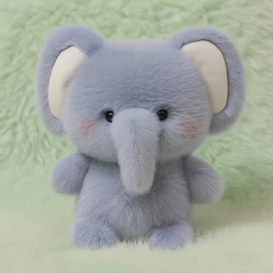 A short, static video of a fluffy, blue-grey plush elephant. It has large ears, a long trunk, and rosy cheeks, and it sits in an upright, empowered posture on a soft, mint-green fluffy surface.