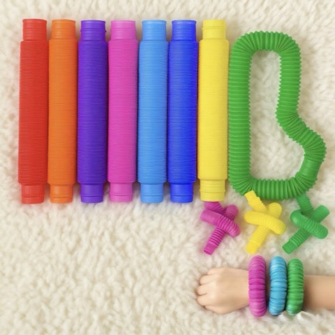 Colorful coiled resistance bands on a textured surface with a child's hand wearing them.