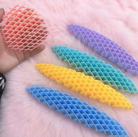 Colorful textured plastic strips on a hand with a soft pink background