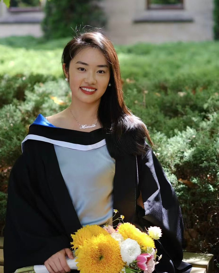 Graduate in cap and gown holding flowers outdoors