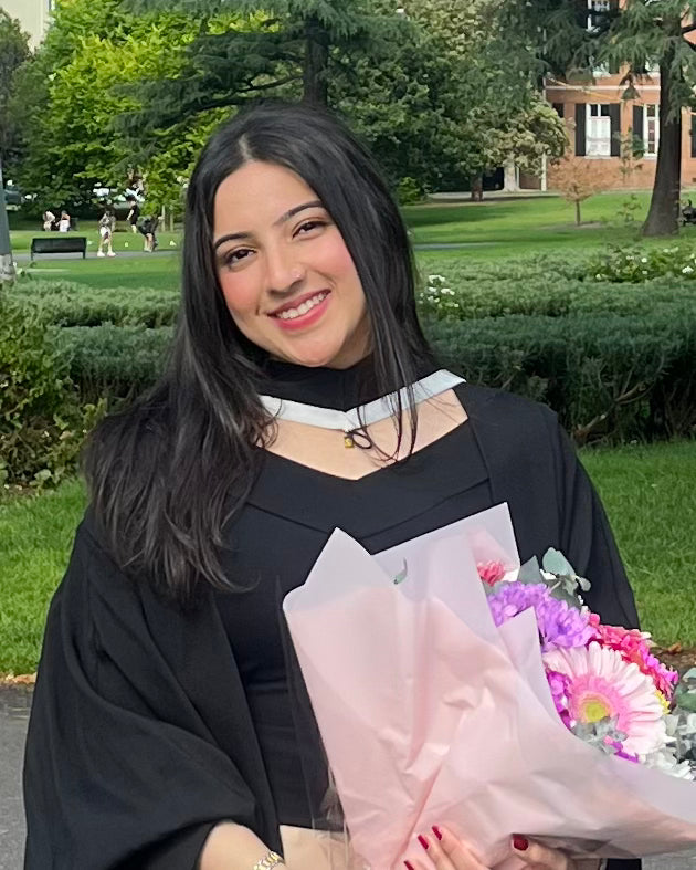 Graduate holding flowers in a park setting