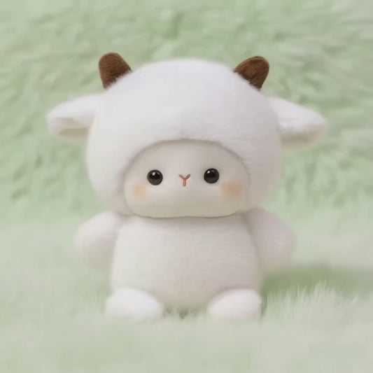 A short, static video of a fluffy white plush lamb. It is wearing a white hood with two small brown horns, and it has large, dark eyes and a sweet, loving expression. The plushie is sitting on a soft, mint-green fluffy surface.